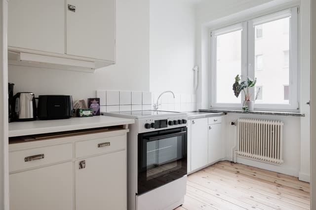Ljust lägenhetsinteriör i Sundbyberg med minimalistisk inredning och grönskande omgivningar