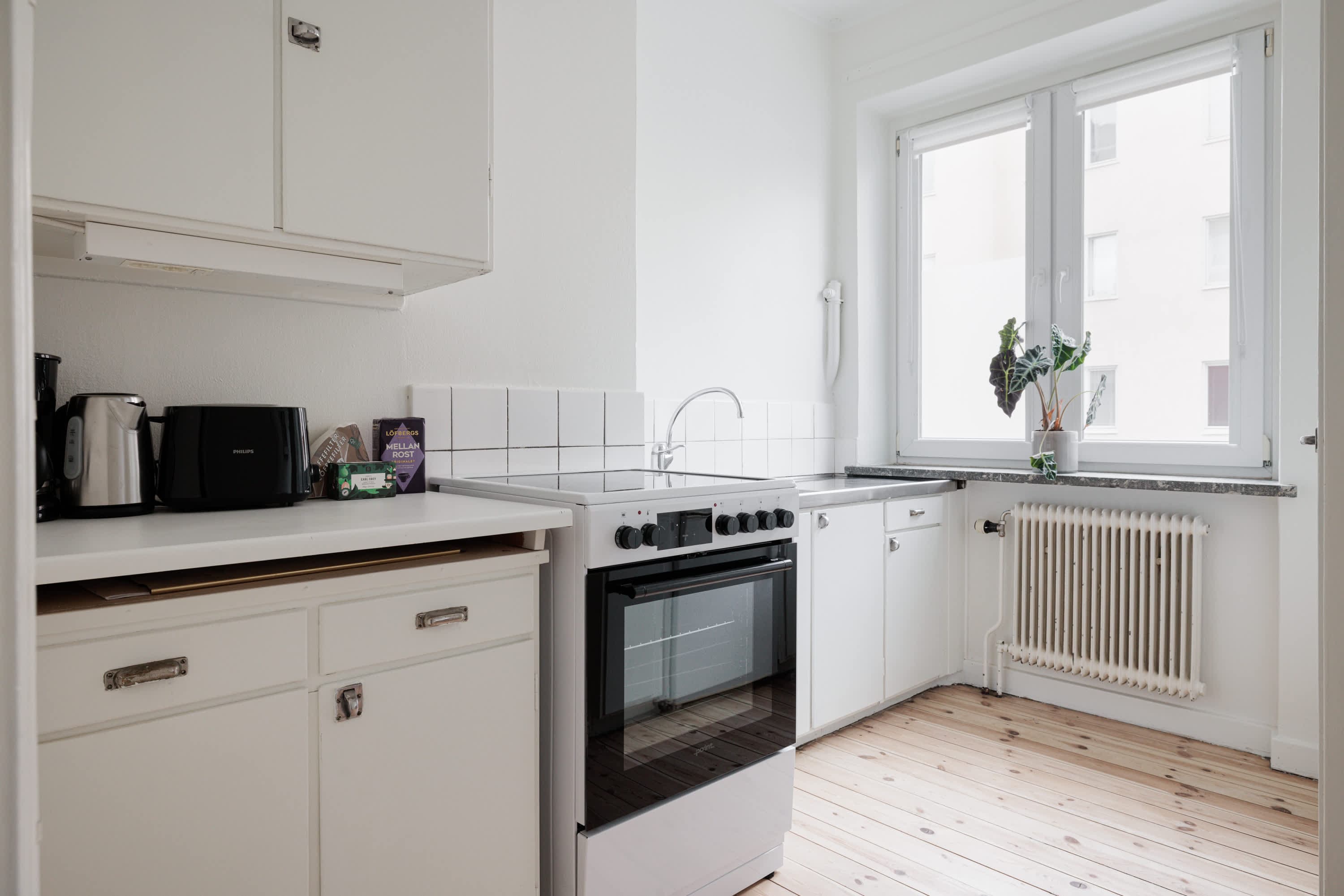 Ljust lägenhetsinteriör i Sundbyberg med minimalistisk inredning och grönskande omgivningar
